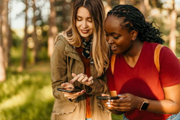 istock Two young women using smartphones in a park 2205814355