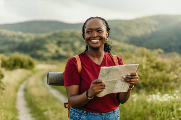 istock Young black woman hiker smiling and holding a map 2205814495