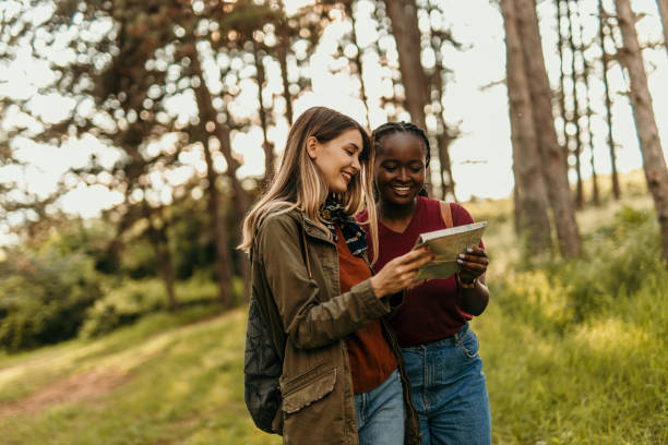 istock Two young women hikers using map and smartphone in forest 2205814910