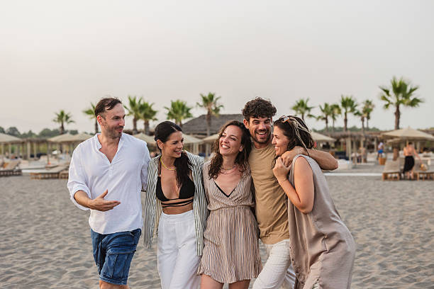 Five friends walking and having fun on the beach at sunset