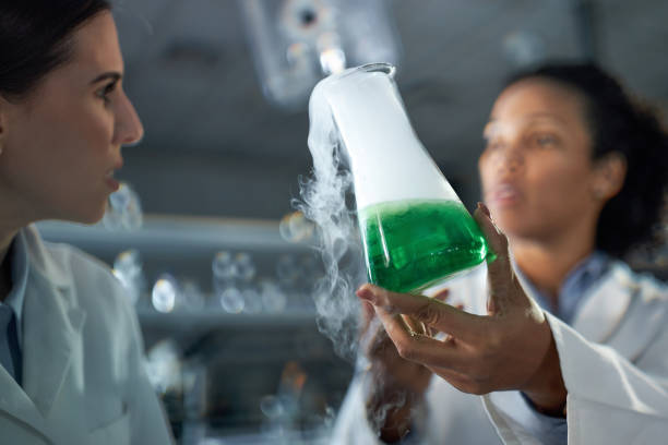 Close up of African American female chemist and her colleague examining toxic fumes from chemical reaction in laboratory.