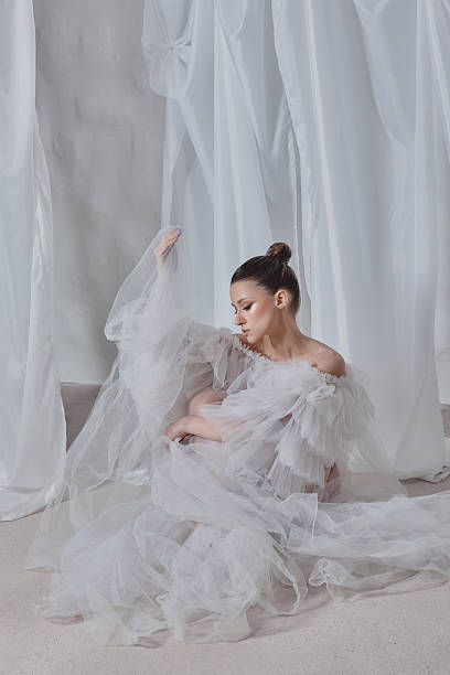 istock model dressed in delicate white fabric gracefully poses on a soft surface, surrounded by sheer drapes 2205820324