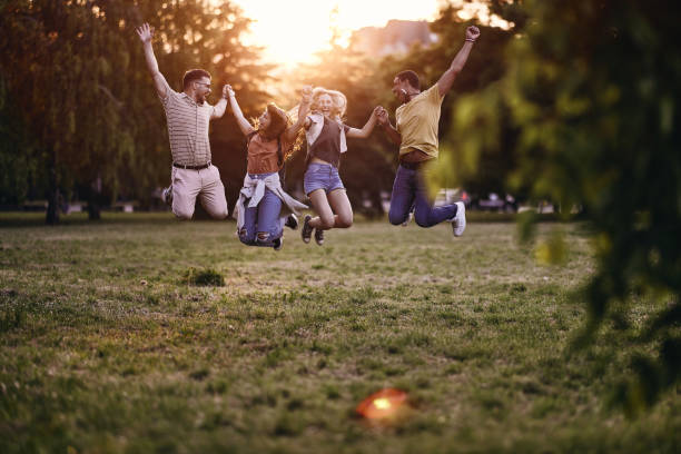 istock Carefree friends having fun while jumping in nature at sunset. 2205820384