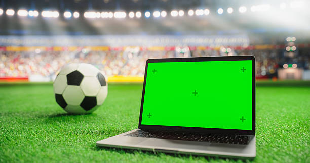 istock Slightly Tilted Laptop Computer with a Green Screen Chromakey Display Placed on Grass Next to a Soccer Ball in an Arena. Template for Marketing and Digital Content in a Sports Environment 2205822890
