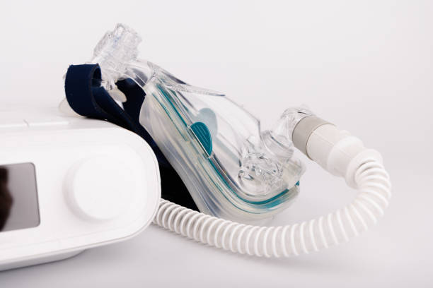 istock CPAP device with digital display, tubing, and mask for sleep disorder treatment on white background 2205823549