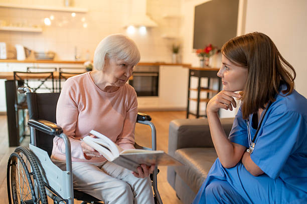 istock Care assistant with her elderly patient enjoying reading and looking happy 2205824798