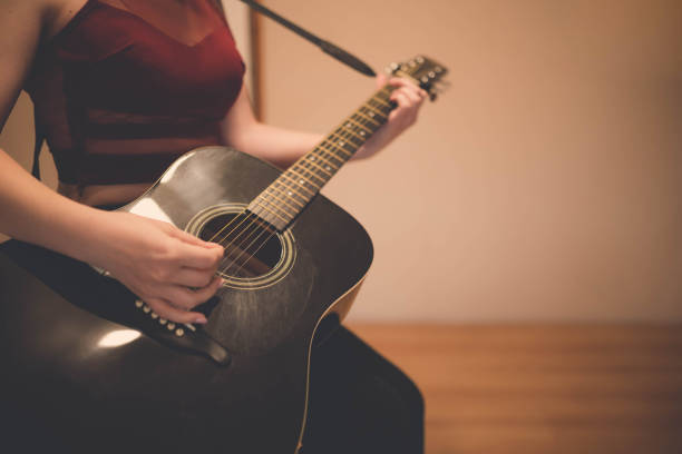 The close-up photo of a woman playing the guitar.