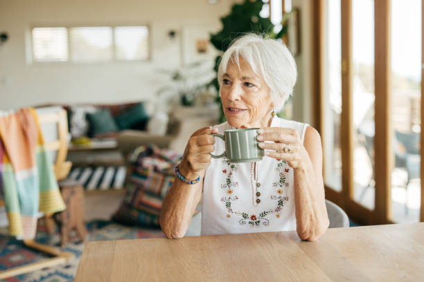 istock A senior lady smiling while drinking coffee in a cozy, well-lit home environment. 2205827167