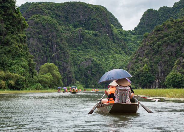 istock People on a boat floating down a river surrounded by tropical lush forests and mountains. Located in Tam Coc Ninh Binh Vietnam 2205828526