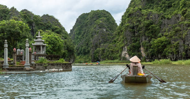 istock People on a boat floating down a river surrounded by tropical lush forests and mountains. Located in Tam Coc Ninh Binh Vietnam 2205828527