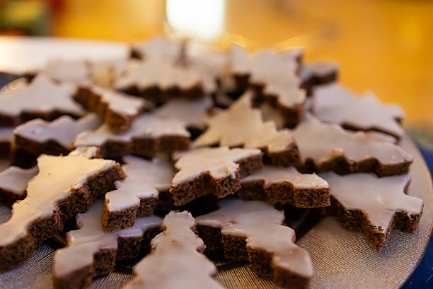 A festive arrangement of Christmas tree-shaped gingerbread cookies covered in white icing, beautifully displayed on a decorative plate. The warm, blurred background adds to the cozy holiday feel, making this image perfect for seasonal baking themes, holiday recipes, or festive lifestyle content.