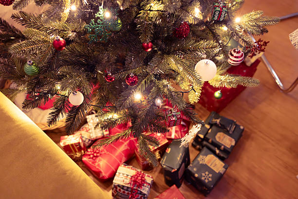 istock Glowing Christmas Tree with Wrapped Presents Beneath 2205828988