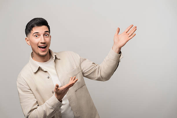 Exciting product or service presentation as a handsome man in his 30s with a big smile confidently points up and to the side with open palms, radiating happiness and trust