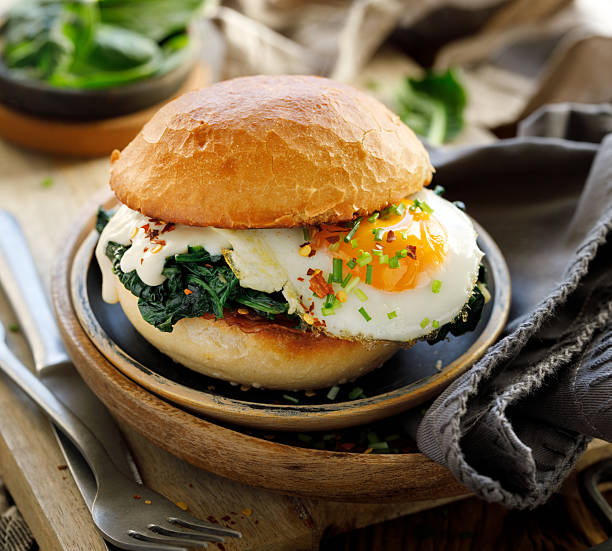 Vegetarian burger with fried egg, spinach and aromatic sauce, sprinkled with fresh chive in a wheat bun