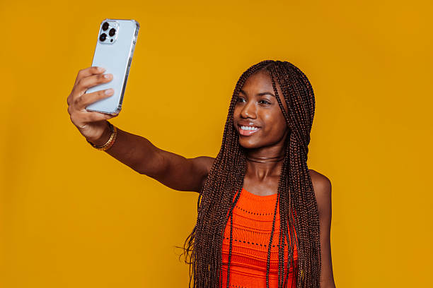 istock Young woman taking selfie with smartphone on yellow background 2205834706