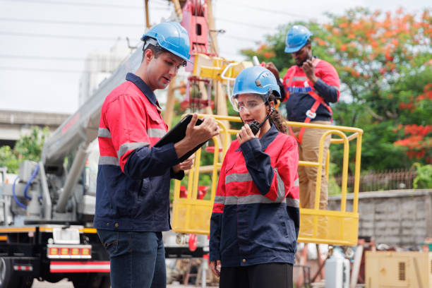 istock A group of technicians, wearing safety helmets and work uniforms, are gathered at a construction site, discussing plans and strategies 2205836811