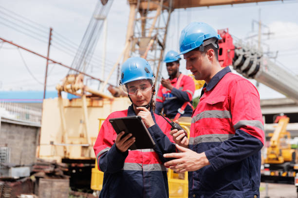 istock A group of technicians, wearing safety helmets and work uniforms, are gathered at a construction site, discussing plans and strategies 2205836839