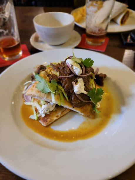 istock Curried lamb with naan bread on a white plate on a wooden table surface, served in a pub or restaurant 2205837216