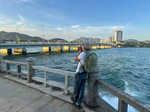 Mature man takes photo by water's edge, Nha Trang