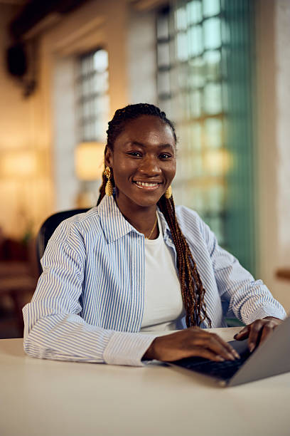 istock Confident Woman Smiling While Working on Laptop in Modern Office Setting 2205842399