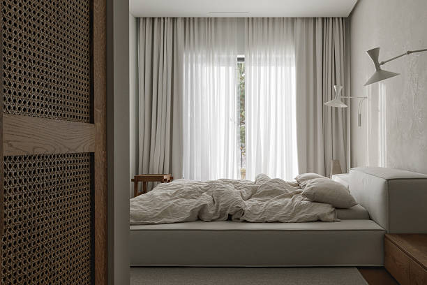 istock wabi-sabi bedroom features an oak bedside table, textured clay wall decor, soft linen bed linens, a neutral grey rug, and a woven rattan wardrobe, creating a harmonious blend of natural materials and serene style. 2205842439