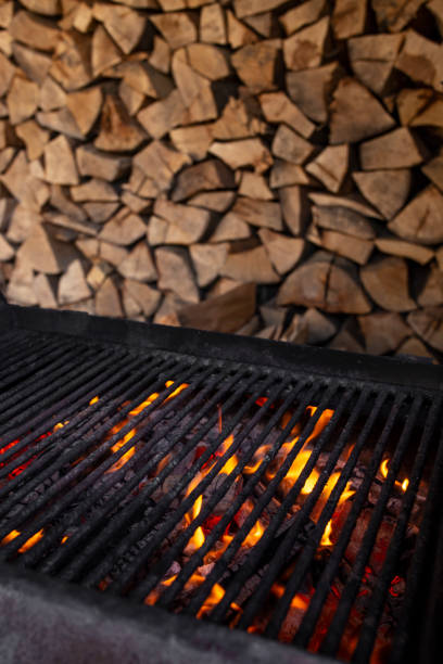 istock Empty burning flames grill with wood stacked in the background, soft focus close up 2205846391