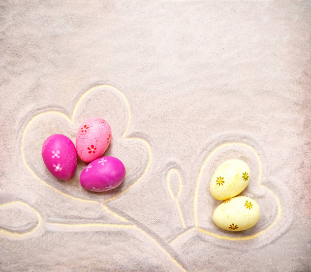 Sand texture with colorful Easter eggs like flowers on the beach. Easter, spring holiday background. Empty place (pattern) for your message. Flat lay. Mock up. Copy space.