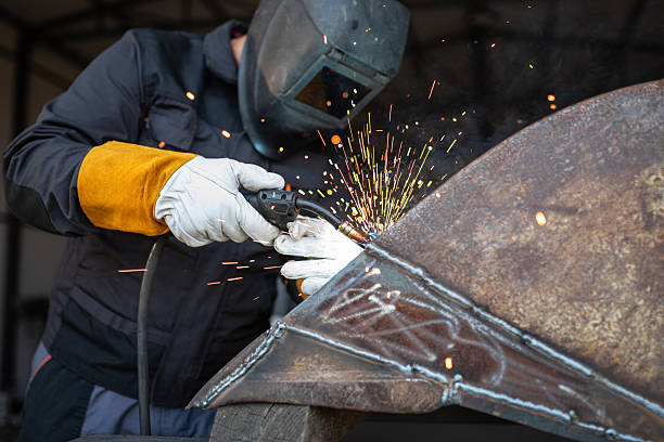 Professional welder joining metal parts using mig mag technique in workshop
