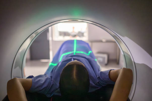 istock Female patient undergoing a scan lying inside a medical imaging machine with alignment lasers 2205851052