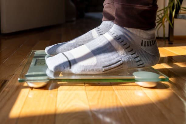 istock Male Stepping on Floor Scale - Weight Loss 2205859328