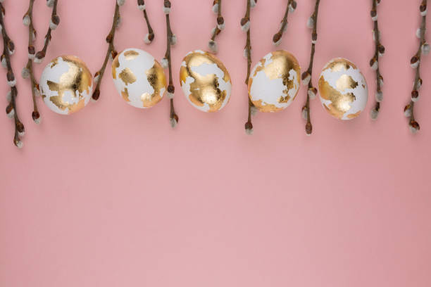 istock Easter gold eggs with willow branches  on a pink background. Easter background.Place for a text. 2205864381