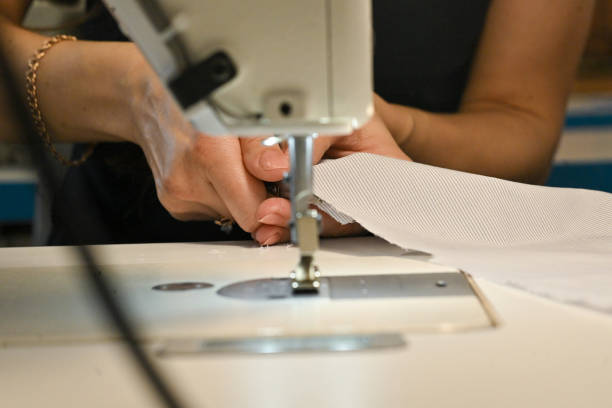 African - american young colleagues having discussion at a clothes manufacturing studio, the  woman sewing at a modern sewing machine