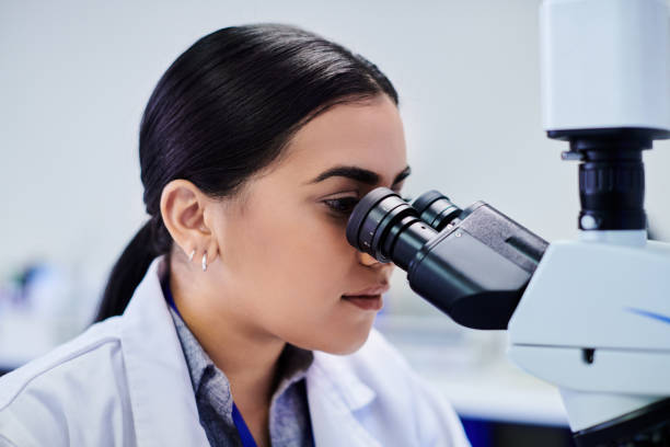 istock A young female scientist looking through a microscope in a clean biochemistry laboratory 2205868307