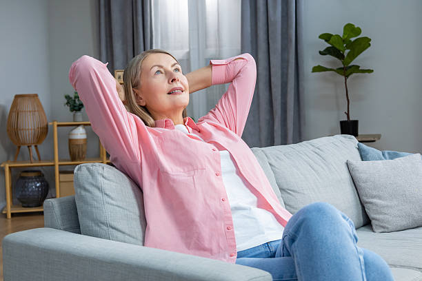 istock Smiling mid aged woman in pink shirt looking contented while spending time at home 2205868736
