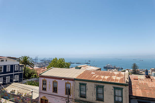 Rooftops of vibrant historic buildings overlooking the ocean. Coastal cityscape with ships in the distance. Picturesque view of urban architecture by the sea.