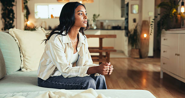 istock Woman, sofa and nervous with thinking in home for decision, worry and reflection on problem. Person, girl and thoughtful in lounge with debt stress, anxiety and wondering with daydreaming in house 2205872435