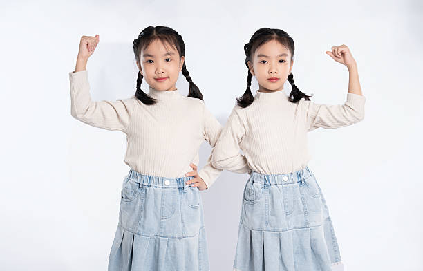 istock Two cute young girls with braids, standing side-by-side, posing confidently against a bright white backdrop. 2205873138