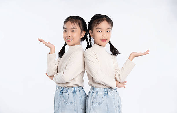 istock Two young girls, back-to-back, presenting something unseen with outstretched hands on a white background. 2205873429