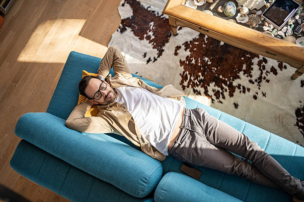 istock Man relaxing on sofa at home enjoying sunlight 2205875686