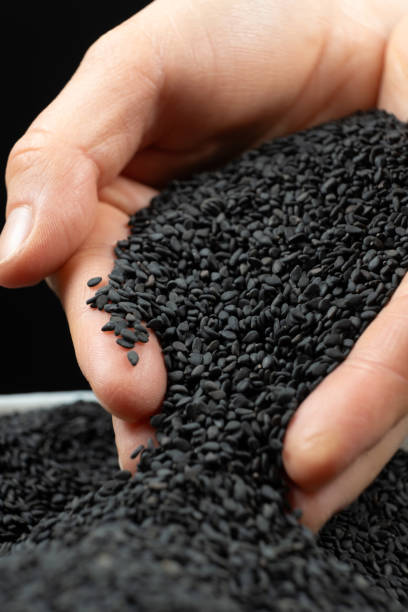 istock Hands pouring black sesame close-up. 2205878849