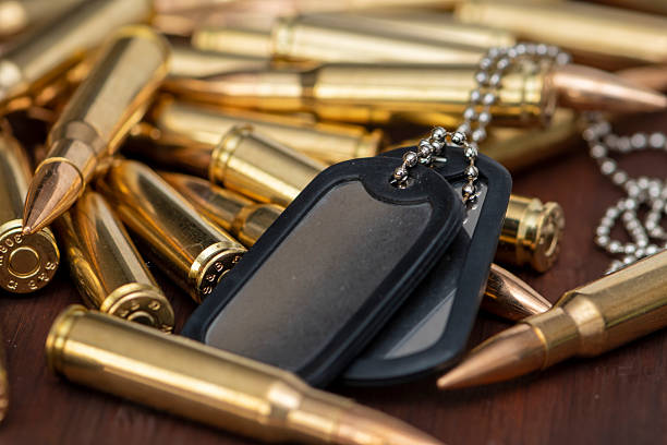 istock Military ammunition and dog tags spread out on a wooden surface. 2205880757