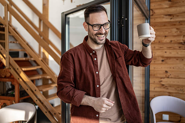istock Cheerful man raising coffee mug and smiling at home 2205881464