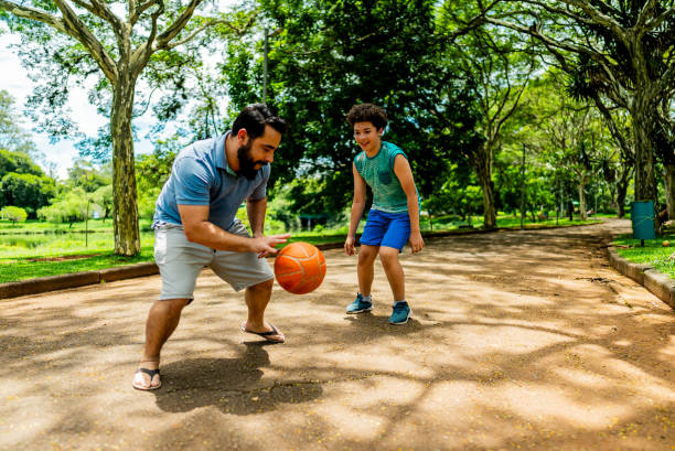 istock Father and son playing basketball in a public park 2205882668