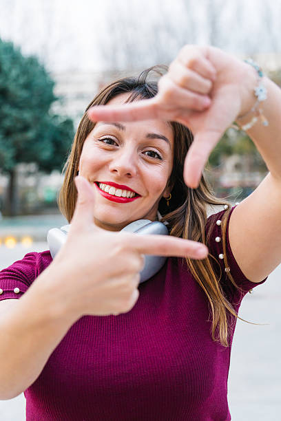 istock Young woman smiling brightly at the camera while framing her face with her hands, showcasing her cheerful personality in an urban setting 2205883369