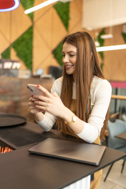 istock Portrait of a young female barista using a phone while working in a cafe 2205883693