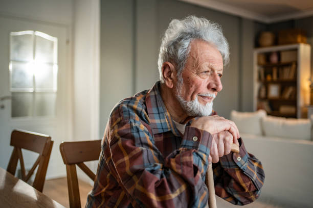 istock Thoughtful senior man sitting at home with walking stick 2205884398