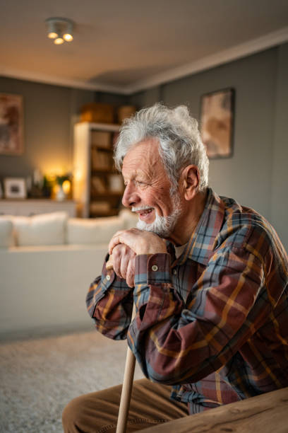 istock Senior man smiling and leaning on walking cane at home 2205884404