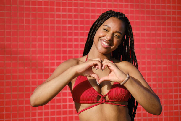 istock Young woman making heart shape with hands on red background 2205884405