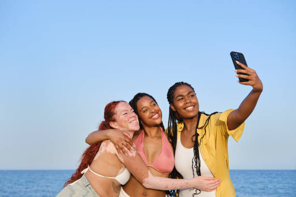 istock Three happy friends taking a selfie at the beach 2205884505