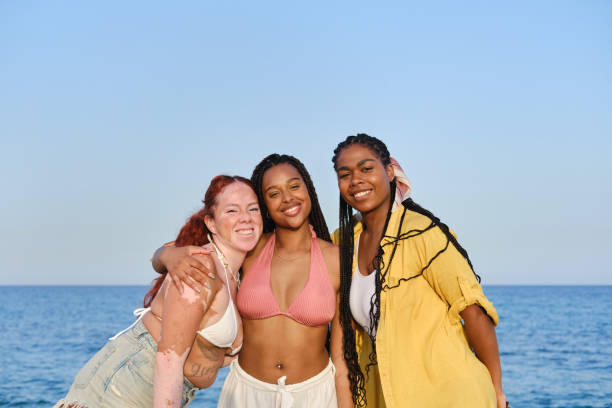 istock Three happy young women embracing on the beach 2205884521